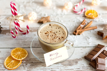 Hot cup of cappuccino or hot milk chocolate with dried orange fruit and cinnamon.