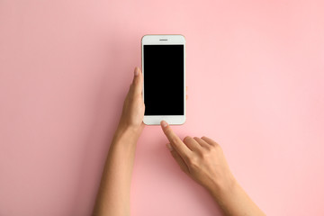 Woman holding modern phone on pink background, top view. Space for text