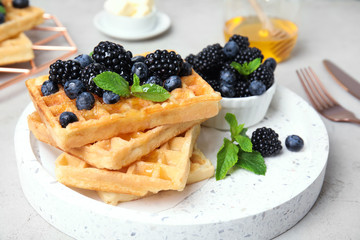 Delicious waffles with fresh berries served on grey table