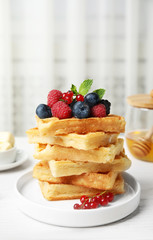 Delicious waffles with fresh berries served on white wooden table indoors