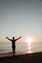 Silhouette of a young man enjoying beautiful sunset on the beach 