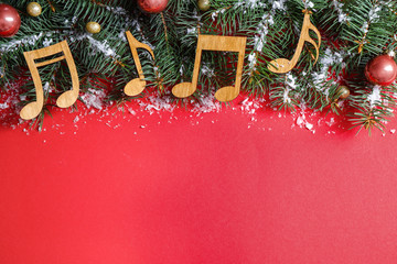 Flat lay composition with Christmas decor and music notes on red background, space for text