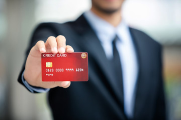 Handsome businessman in black suit showing his credit card to make a payment.