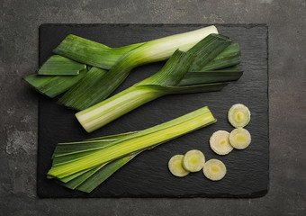 Fresh raw leeks on grey table, flat lay. Ripe onion