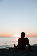 Silhouette of a young man enjoying beautiful sunset on the beach 