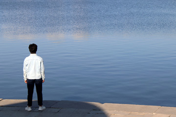 Fototapeta premium young man stands on the embankment of the city pond