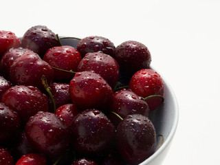 A bowl full of freshly washed cherries on white.
