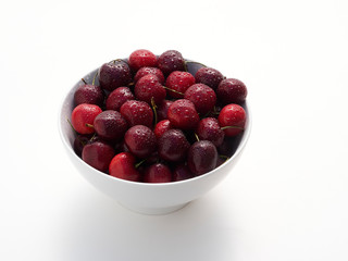 A bowl full of freshly washed cherries on white.