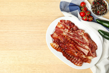 Slices of tasty fried bacon on wooden table, flat lay. Space for text
