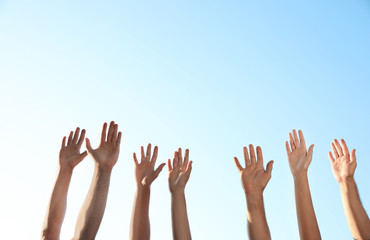 Group of volunteers raising hands outdoors, closeup
