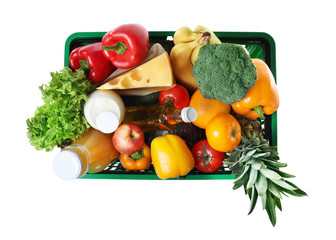 Shopping basket with grocery products on white background, top view