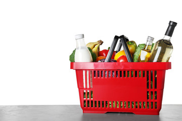 Fototapeta premium Shopping basket with grocery products on grey table against white background. Space for text