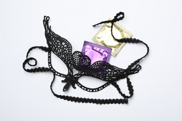 Lace mask and condoms on white background, top view. Sex game