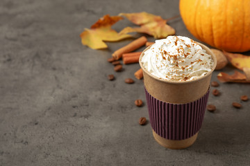 Paper cup with tasty pumpkin spice latte on grey table. Space for text