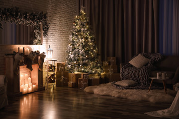 Stylish interior with beautiful Christmas tree and artificial fireplace at night