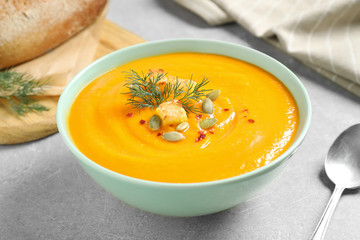 Delicious pumpkin soup in bowl on grey table