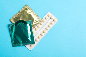 Condoms and birth control pills on light blue background, flat lay with space for text. Safe sex...