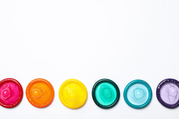 Colorful condoms on white background, top view. LGBT concept