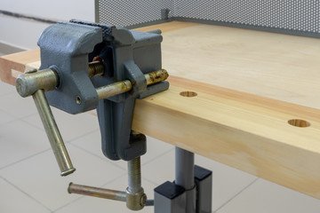 Vise attached to the workbench. Workplace of a carpenter. Close-up. School or home workshop.