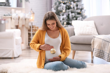 Young pregnant woman with Christmas decoration at home