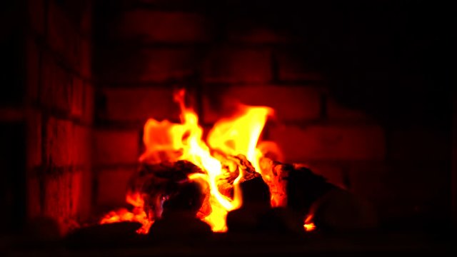 Red fire burns in a brick fireplace - firewood burns out in a stove