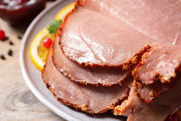 Delicious ham served with garnish on wooden table, closeup