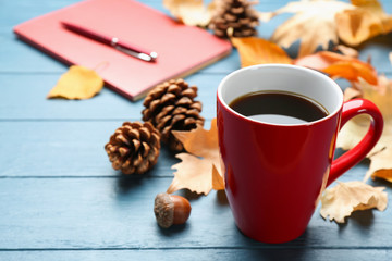 Cup of hot drink and leaves on blue wooden table. Cozy autumn atmosphere