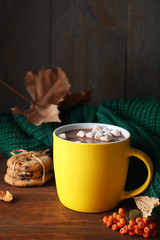 Fototapeta na wymiar Cup of hot drink and knitted sweater on wooden table. Cozy autumn atmosphere