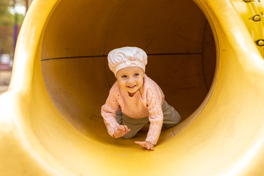  little girl crawling through the tunnel in the playground autumn  day - Powered by Adobe
