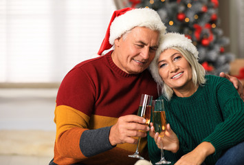 Happy mature couple with glasses of champagne at home. Christmas celebration