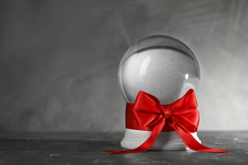 Beautiful Christmas snow globe with red bow on grey table, space for text