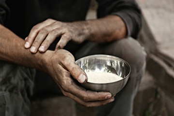 Poor homeless man with bowl of rice outdoors, closeup