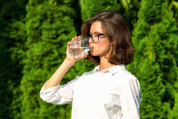 Young woman drinks water in garden