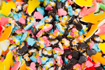 a scattering of marmalade sweets of different colors, mainly in the form of penguins with dolphins at the edges.