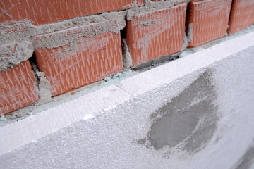 Close-up detail of brick house wall with rigid styrofoam insulation sheet. Modern technology of construction, renovation and energy saving. Alternative for mineral wool, warm comfortable house concept