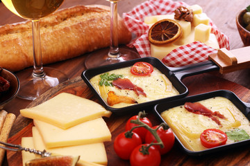 Delicious traditional Swiss melted raclette cheese on diced boiled or baked potato and baguette served in individual skillets with salami..