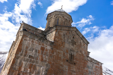 Fototapeta premium Medieval stone temple on the background of a blue sky. Gergeti, Stepantsminda, Georgia, May.2017