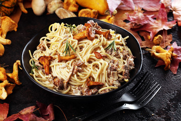 pasta with organic chanterelles. portion of spaghetti pasta with fried chanterelles in a creamy garlic sauce with cheese on a table
