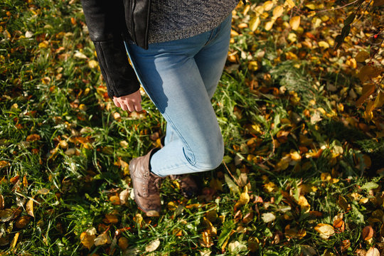 Woman In Blue Jeans And Leather Boots Standing On Yellow Leaves In Autumn.