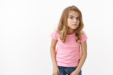 Fototapeta premium Intrigued smart, nosy and curious young little girl, peeking, frowning look strict and serious forward, hear something, stare suspicious uncertain, eavesdropping, overhear interesting conversation