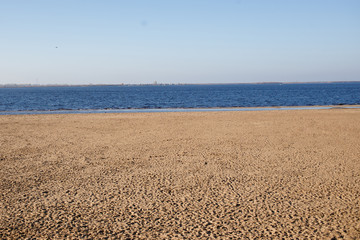 Fototapeta na wymiar Minimalistic landscape empty sand beach and deep blue water in sunny day in autumn.