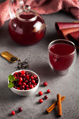 red berry tea of ​​their cranberries, black tea, cinnamon, ginger and mint in a teapot with a mug and bowl of cranberries