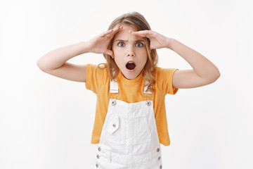 Impressed gasping shocked pretty blond girl, frowning disappointed, hold hands on forehead look...