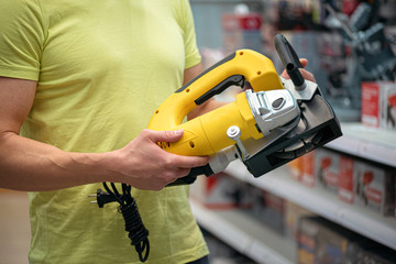 Worker buying a new electric wall chaser in construction store.
