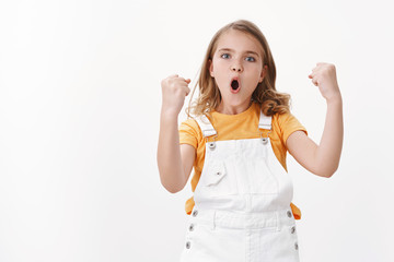 Amused cheerful young blond girl child, celebrating victory, feeling excited like winner, fist pump...