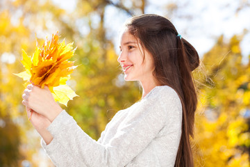 Pretty brunette little girl posing in autumn park background