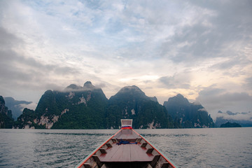 Head of Thai’s traditional long tail boat blur at foreground with mountains in the background at Ratchaprapa Dam, Surat Thani, Thailand. 