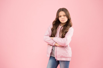 Stylish outfit for crispy autumn days. Stylish girl keep arms crossed in casual outerwear. Serious little child with stylish autumn look on pink background. Stylish and comfortable, copy space