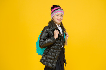 Schoolgirl fashion outfit. Fall autumn winter. Child with backpack. Fashion shop. Girl wear knitted hat and jacket yellow background. Fashion concept. Warm clothing. Buy clothes for school season