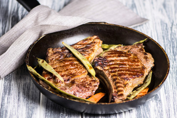 grilled beef steak on a bone in a pan with asparagus